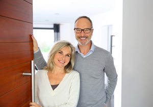 Senior couple welcoming people to enter home